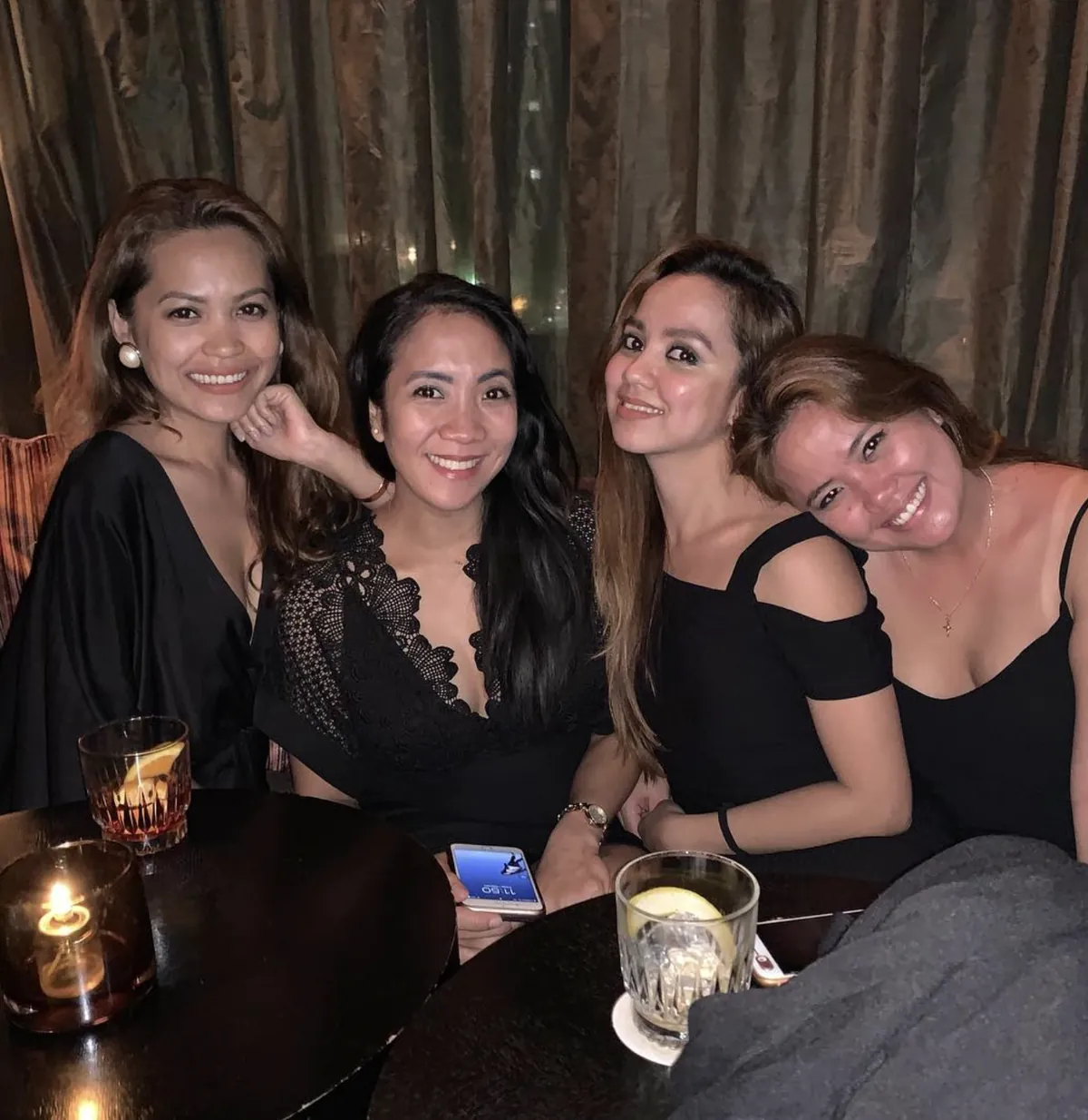 Four friends smiling around a candlelit table