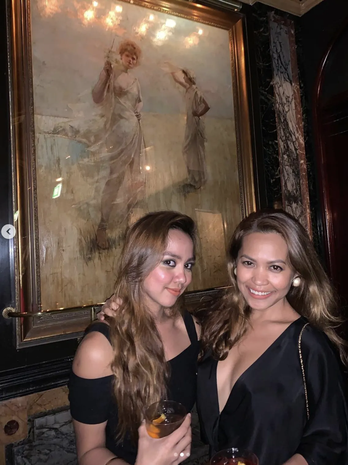 Two friends in front of a large framed painting