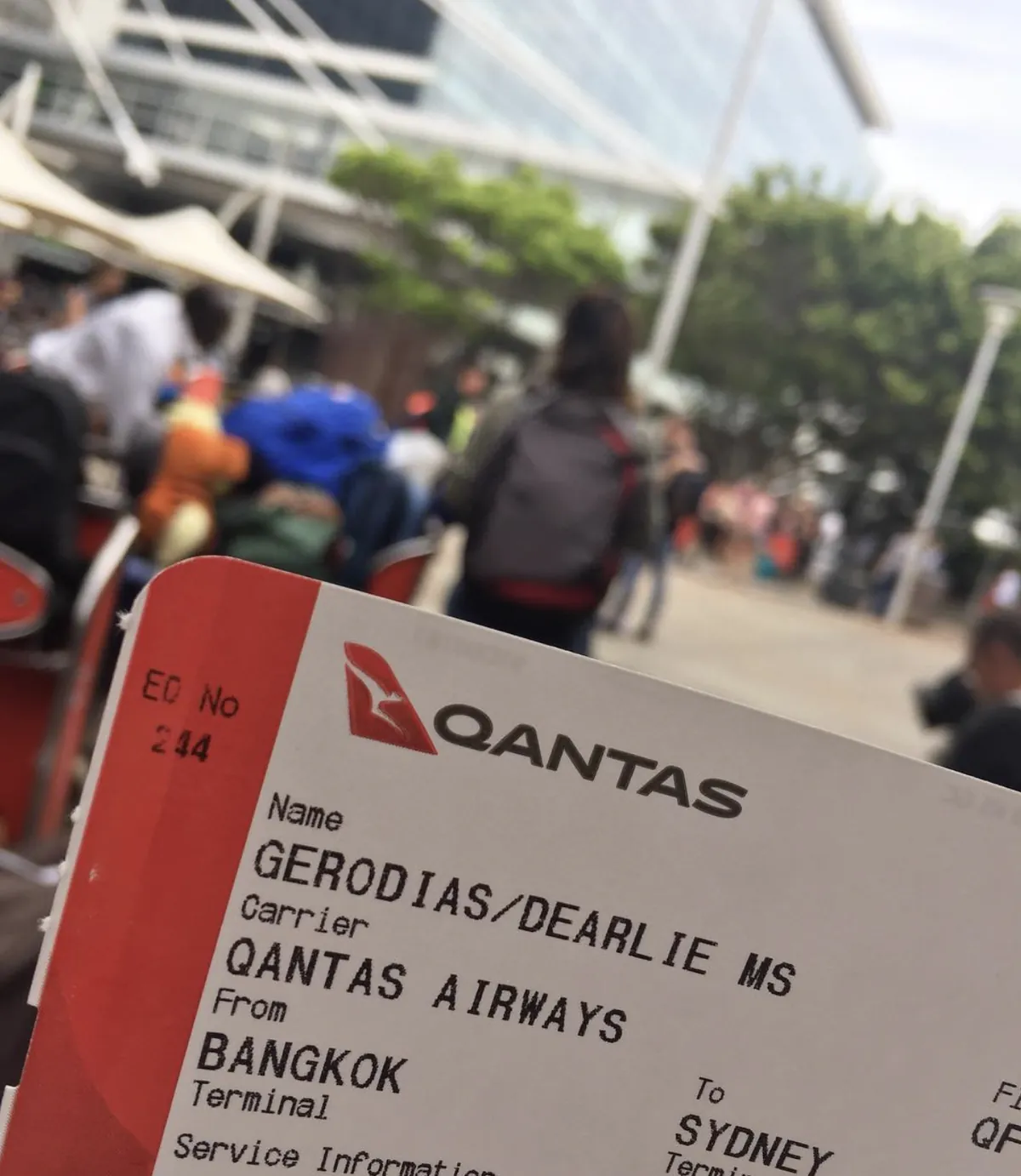 Dee holding a Qantas boarding pass from Bangkok to Sydney