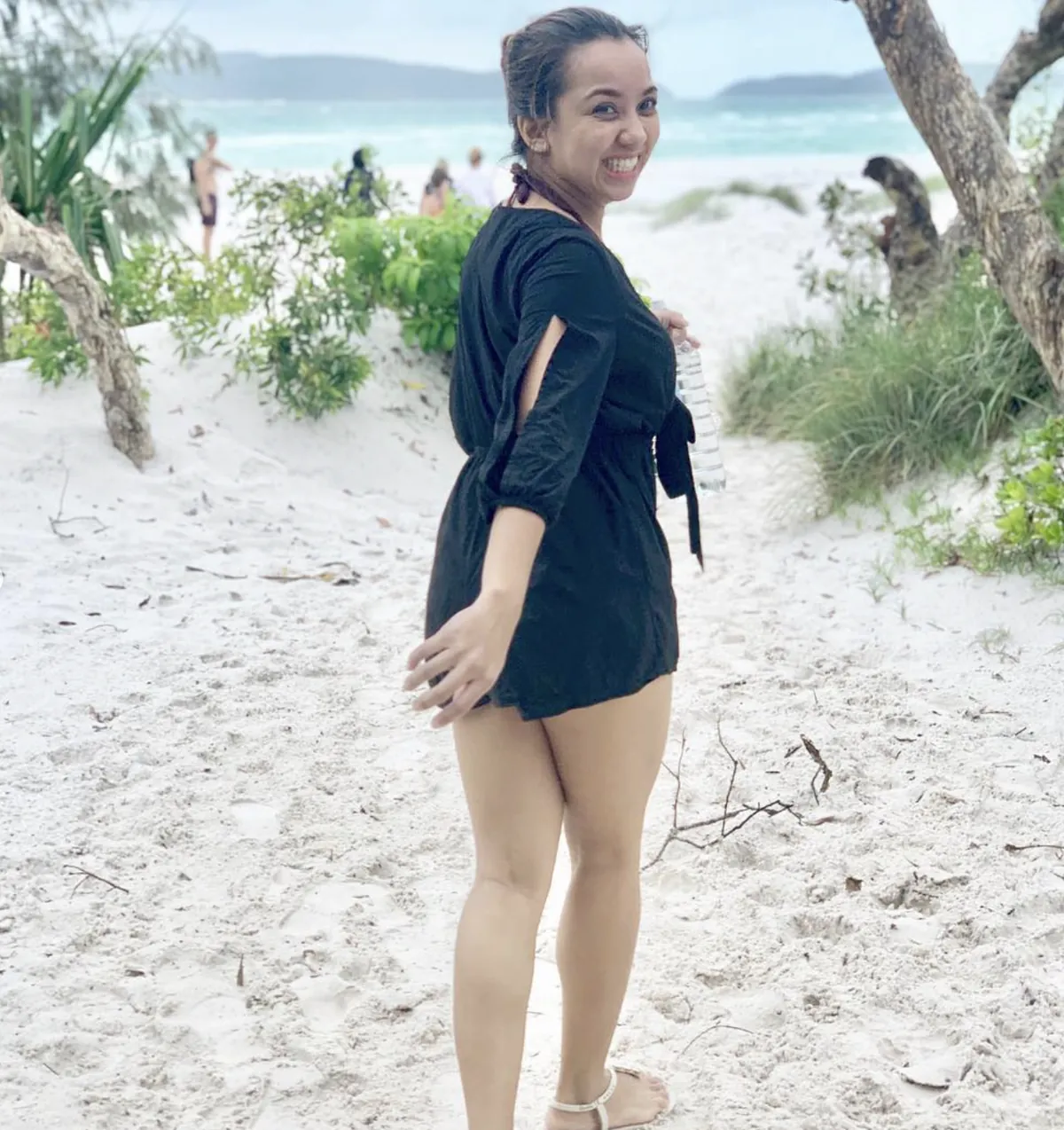 Dee looking back over her shoulder on a white sand path
