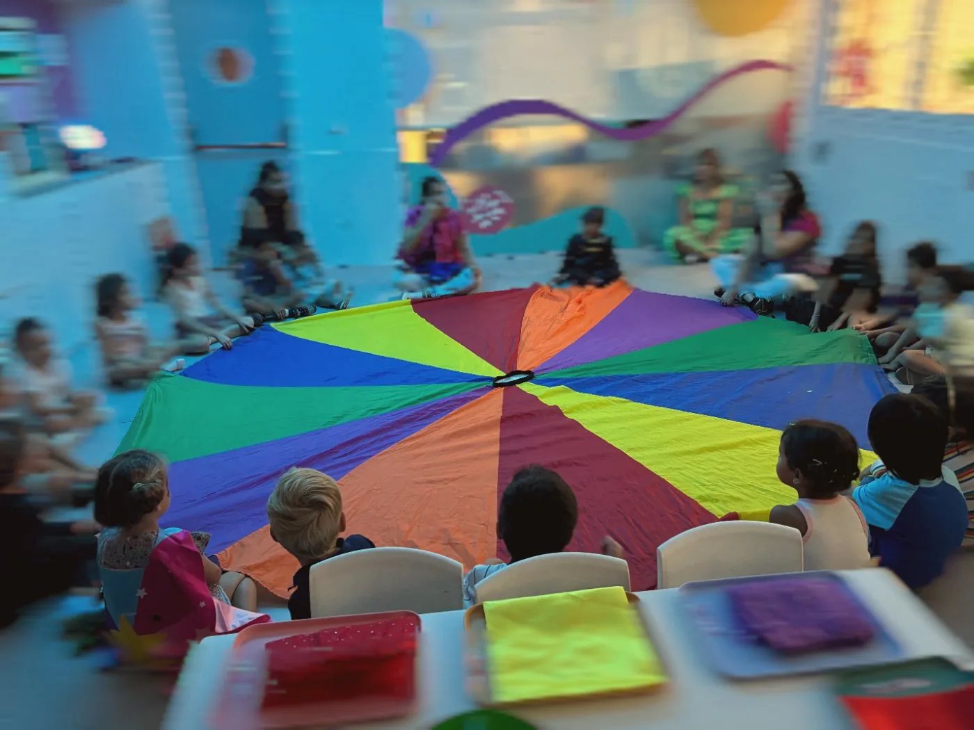 Children sitting around a rainbow parachute