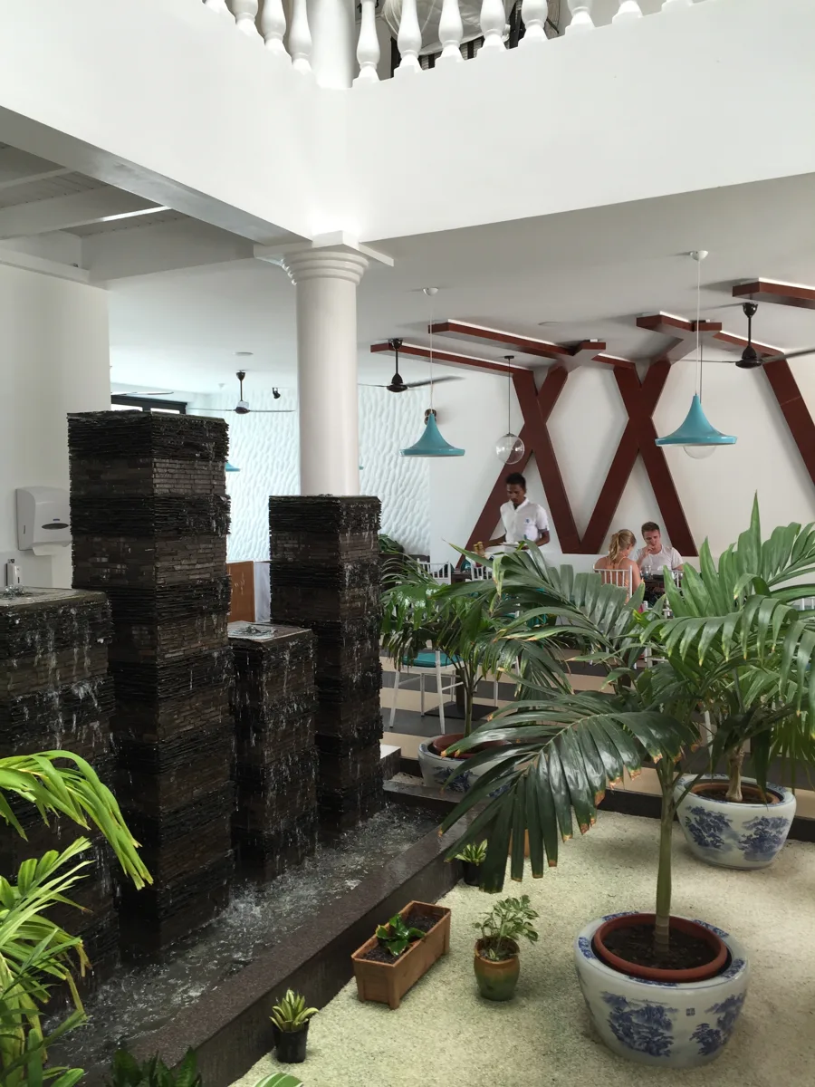 A bright dining room on Maafushi with a stone water feature and potted palms