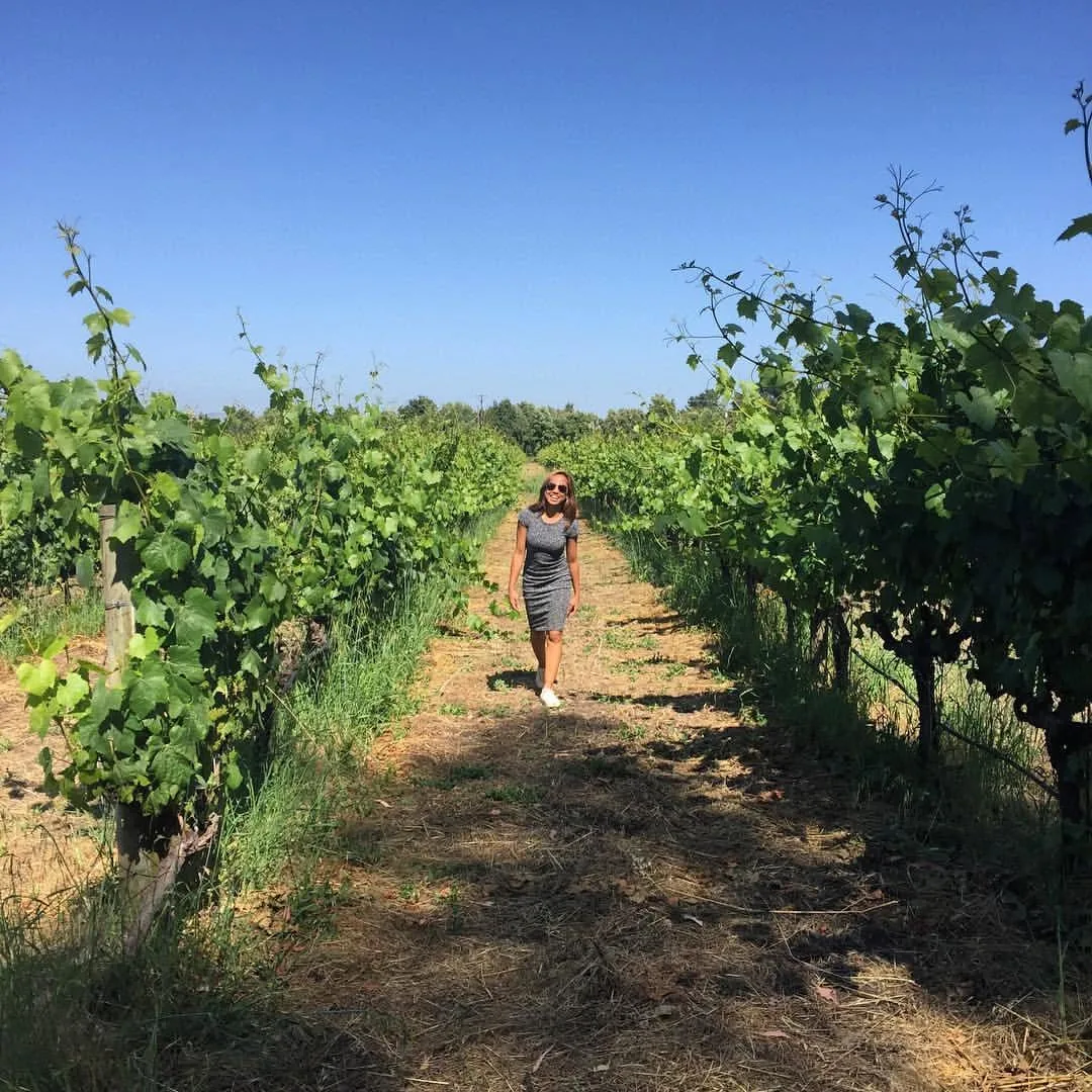 Dee walking between rows of grapevines