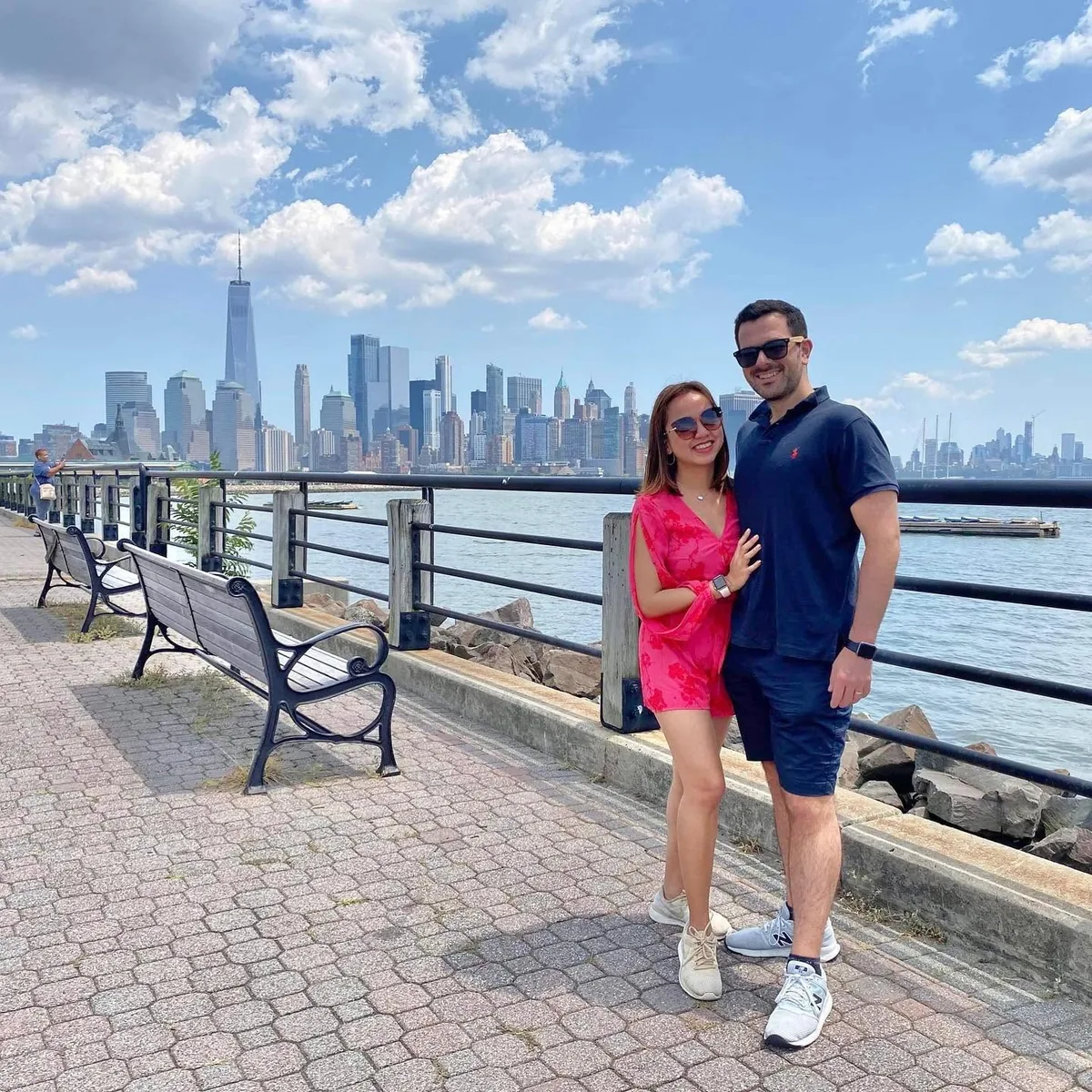 Dee and her husband by the river with the Manhattan skyline behind
